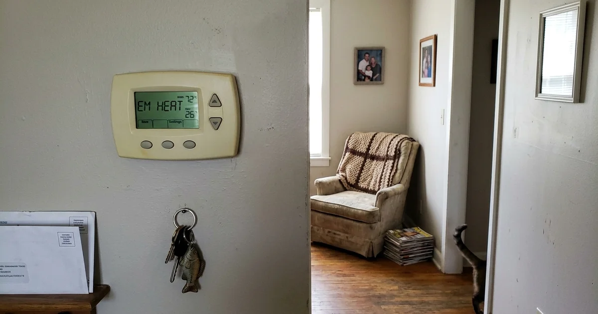 Thermostat screen showing the EM HEAT indicator on a hallway wall