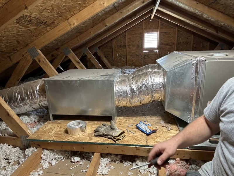 Whole-home dehumidifier installed beside an air handler in an attic